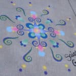 Sidewalk chalk drawing with dark blue swirls and dots of blue pink yellow on gray sidewalk