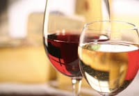 closeup of white wine in glass with larger glass of red wine behind, blurred background