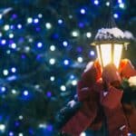 Old-fashioned black Lamppost with red bow and background of many tiny blue and white lights