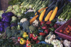 large vegetable display of red cabbage, broccoli, yellow squash, red & green bell peppers, cauliflower, celery, cherry tomatoes