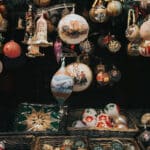 many antique Christmas ornaments of different shapes hanging over boxes of elaborate ornaments