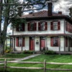 Barton House Bloomsburg Pa - beige siding with burgundy shutters and door, porch around front and side large tree in front