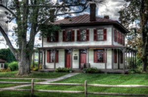 Barton House Bloomsburg Pa - beige siding with burgundy shutters and door, porch around front and side large tree in front