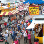overhead shot of visitors gathered between vendor booths like Benton Cider Mill as they enjoy food at the Bloomsburg Fair