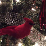 close up of christmas tree with white lights red cardinal and red teardrop ornaments