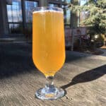 full glass of golden beer on wooden board outside brew pub