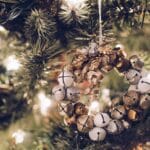 closeup of wreath of mini gold and white jingle bells on Christmas tree with white lights