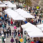 birds eye view of tops of white tents with crowds milling around them