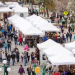 birds eye view of tops of white tents with crowds milling around them