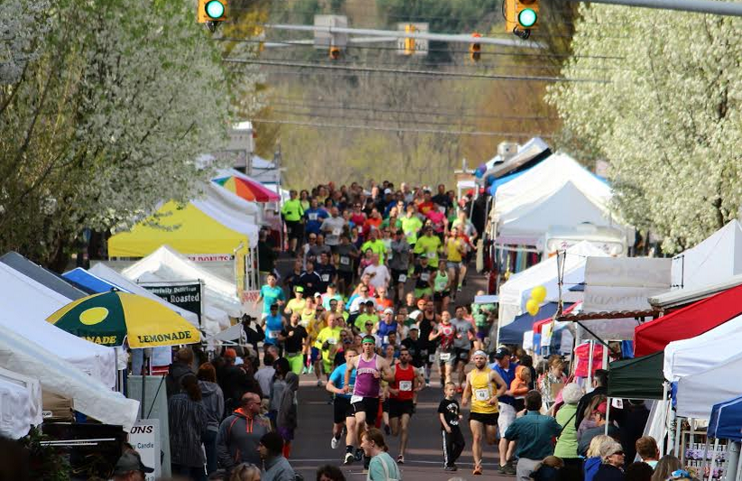 many people running through the street for North Central Marathon with food vendors lined along the sides