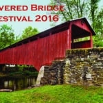 Red covered bridge with stone wall approach in foreground, green grass, trees in background Text: Covered Bridge Festival 2016