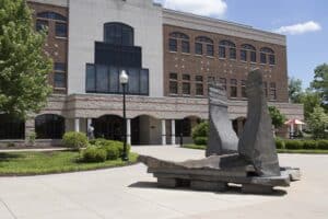 Sculpture -2 large opposing stacked stone forms arranged to allow seating with red brick and stone library building behind