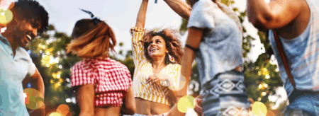 people dancing at an outdoor summer concert surrounded by warm lights and trees