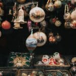 many colors antique christmas ornaments hanging over woven baskets with more ornaments