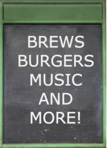 green framed blackboard with white chalk text: Brews Burgers Music and More!