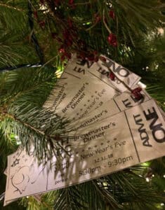 4 tickets to Brewmaster's Dinner fanned out against christmas tree with white lights