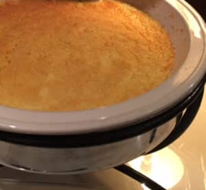 Cheesy grits in cream color round casserole with wrought iron holder