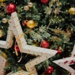 closeup of christmas tree decorated with large white stars and smaller gold and red balls