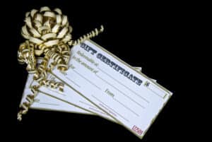 stack of 3 gift certificates tied with gold ribbons on black background