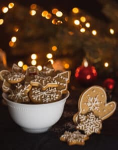 gingerbread snowflakes and stars with white icing in white bowl christmas lights behind