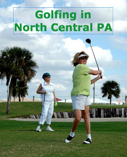 woman in chartreuse shirt, white pants, visor swing golf club, woman in white standing behind, sand trap, trees behind Text: Golfing in North Central PA