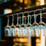two rows of clear wine glasses hanging upside down over bar