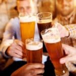 Two men in a pub toasting with four different glasses of beer