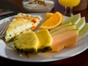 breakfast quiche on white plate with orange & pineapple slices