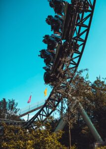 A rollercoaster full of people descends down a slope under a clear blue sky.