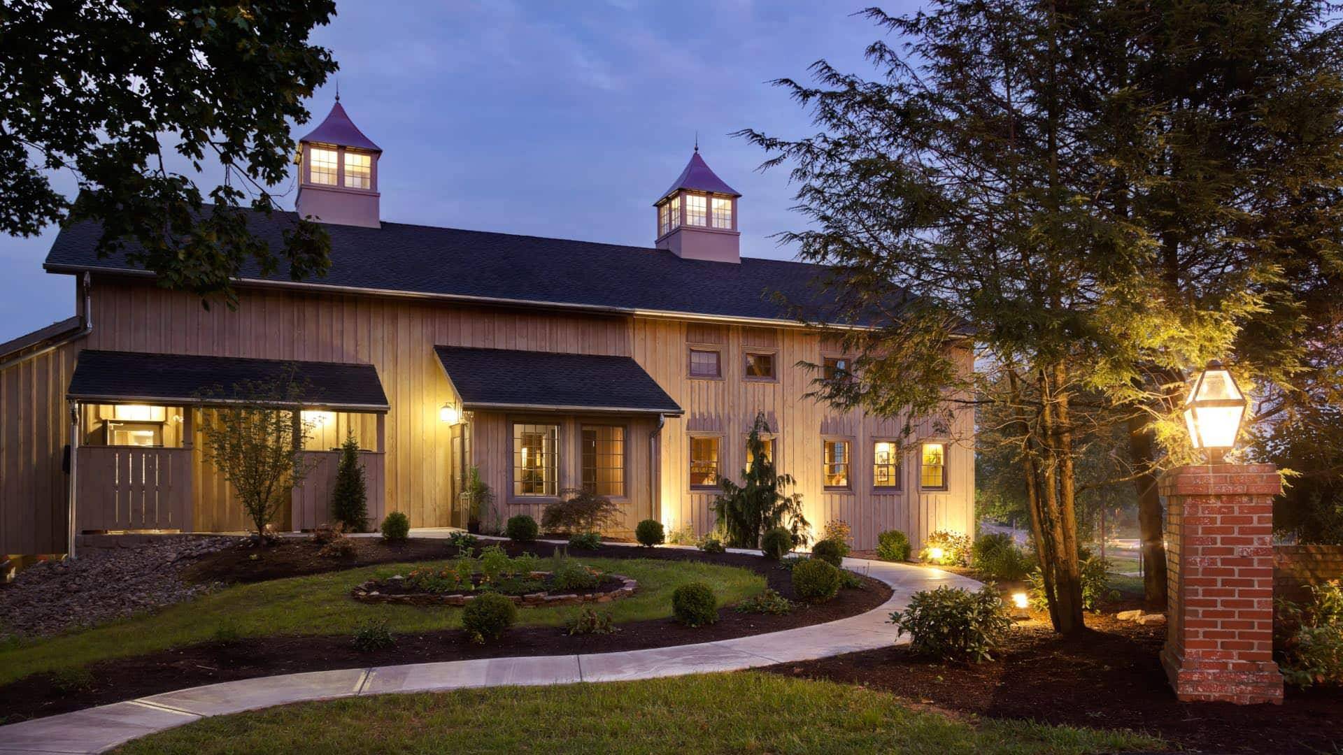 Exterior view of the Brewery at dusk surrounded by green shrubs, grass, and trees