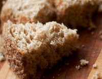 portions of 3 wedge-shaped pieces of  whole grain bread with darker crust on brown wood