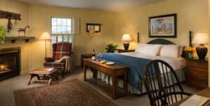 Inn room with fireplace wingchair king bed with blue & white bedding chair desk