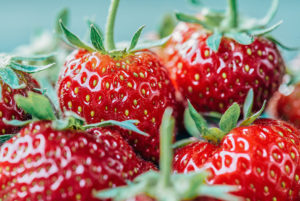 cluster of 4 ripe red strawberries with green stems