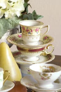 patterned tea cups & saucers stacked vertically with white hydrangia in background