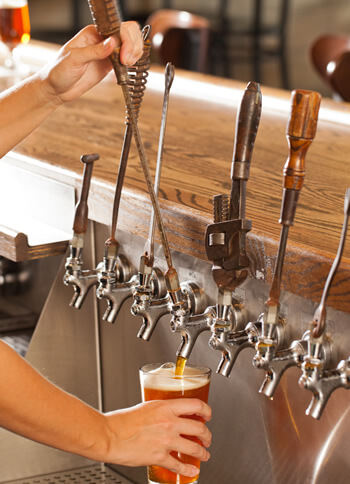hands of worker pouring a fresh draft beer from tap