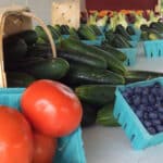 closeup of red tomatoes blueberries cucumbers in baskets at farm stand