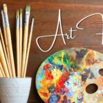 Container of art brushes, a paint palette, and paints with text ArtFest