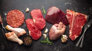 assortment of fresh raw meat on a black surface