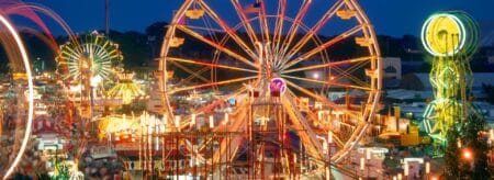 aerial view of a county fair at night with rides and tents all lit up