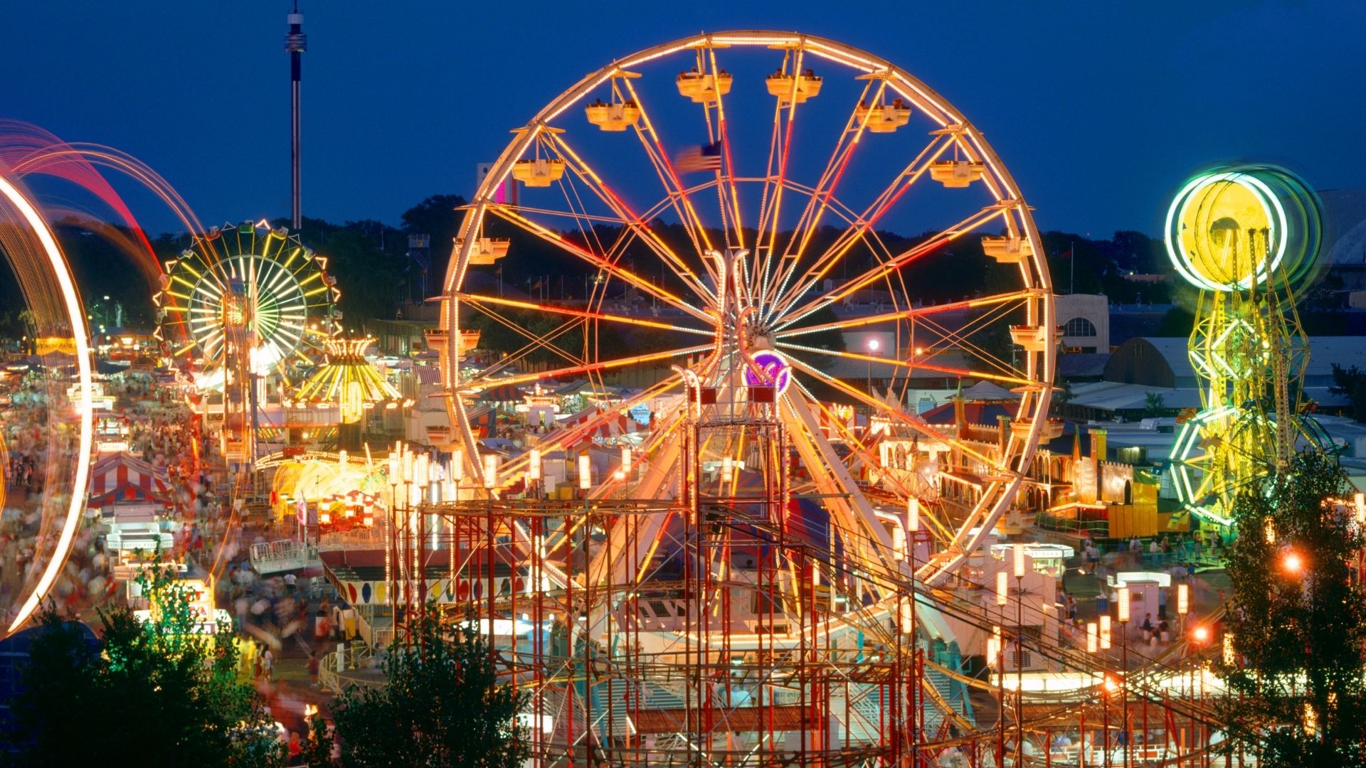 aerial view of a county fair at night with rides and tents all lit up