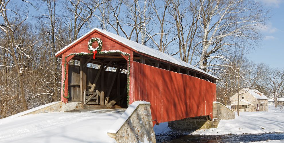 A red, covered bridge dusted in snow 