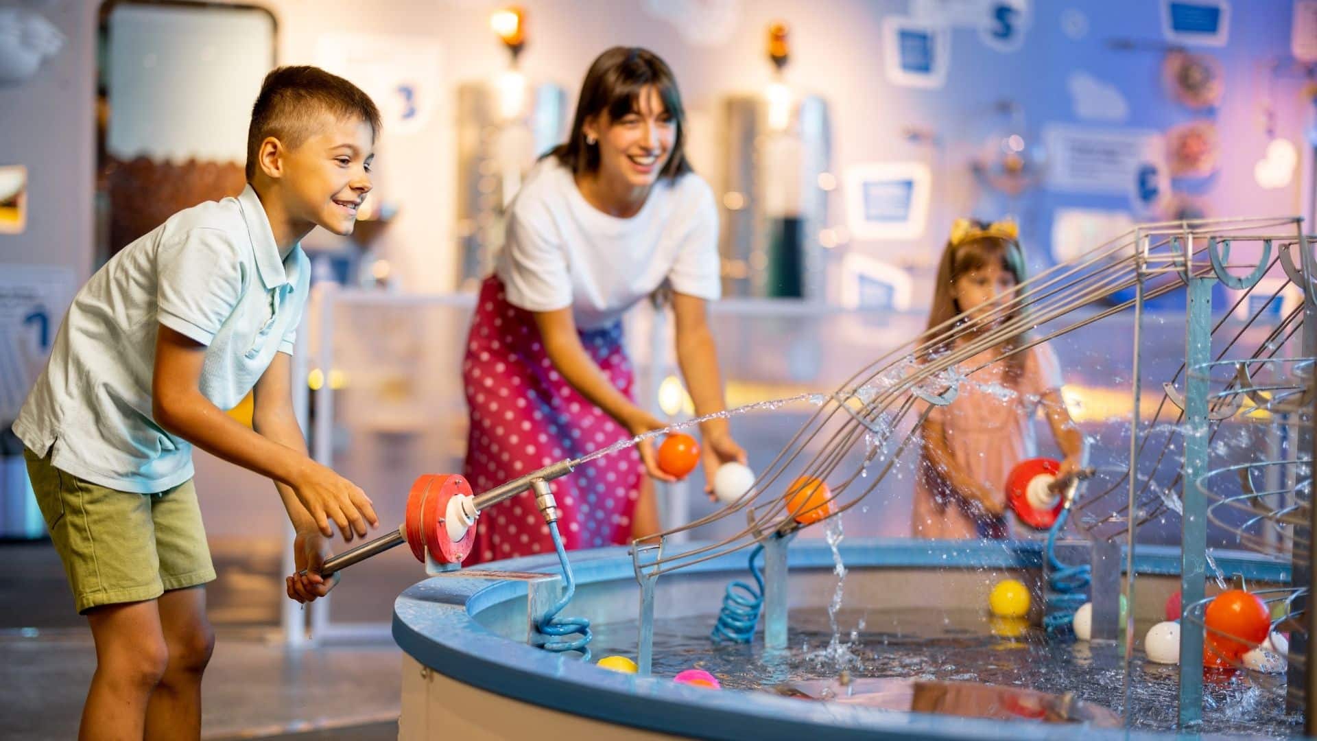 mom and kids having fun with a hands-on exhibit at at sciencee museum