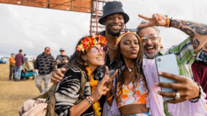 group of friends dressed in colorful outfits taking a selfie at an outdoor festival 