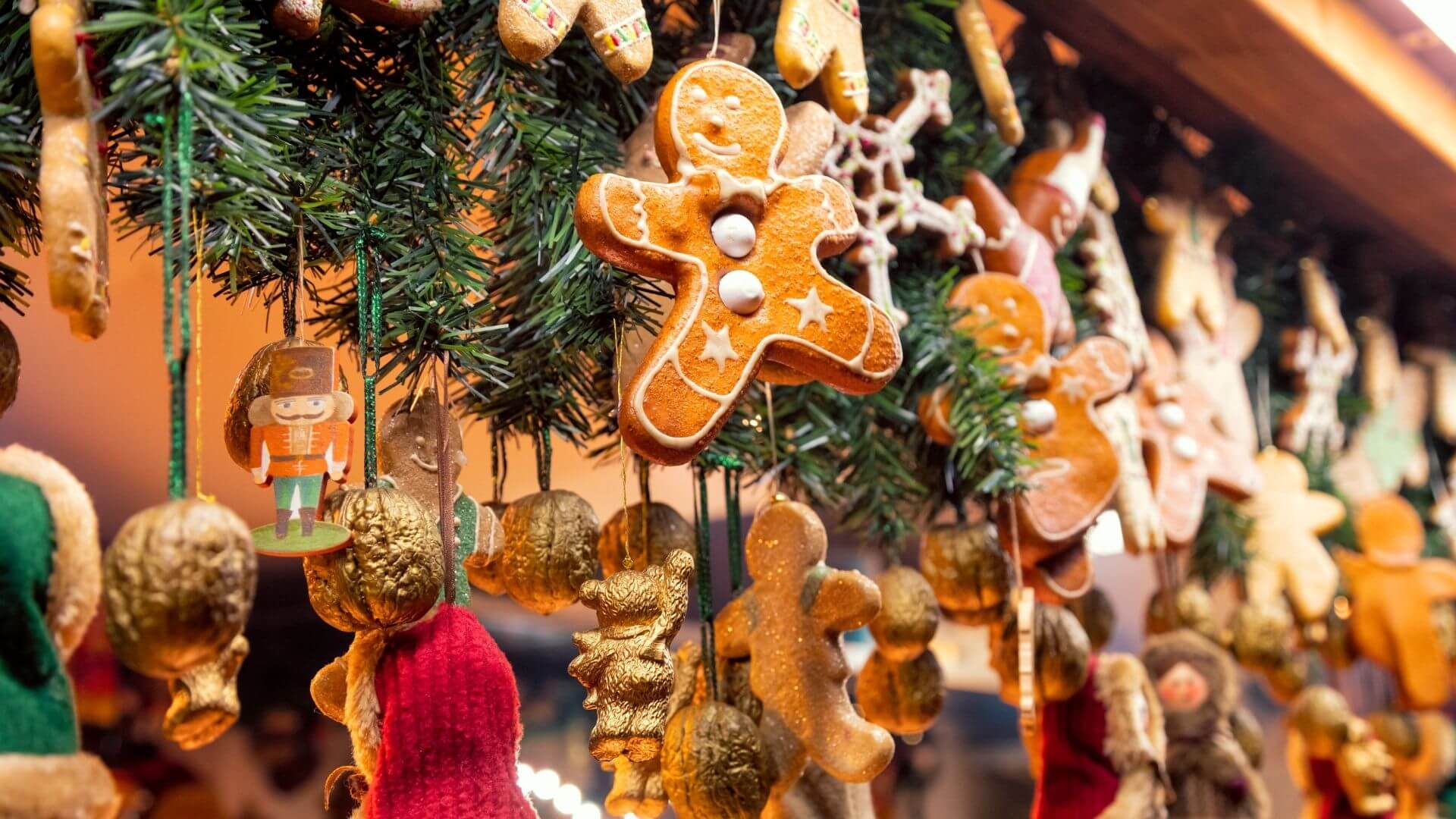 Gingerbread ornaments hanging from greenery at a festive holiday market.