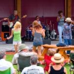 People gathered for an outdoor concert sitting in lawn chairs