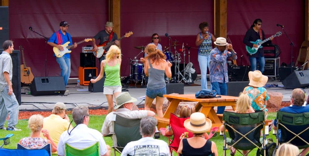 People gathered for an outdoor concert sitting in lawn chairs