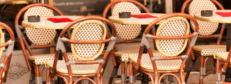 outdoor seating at a cafe with woven bistro chairs and round tables set