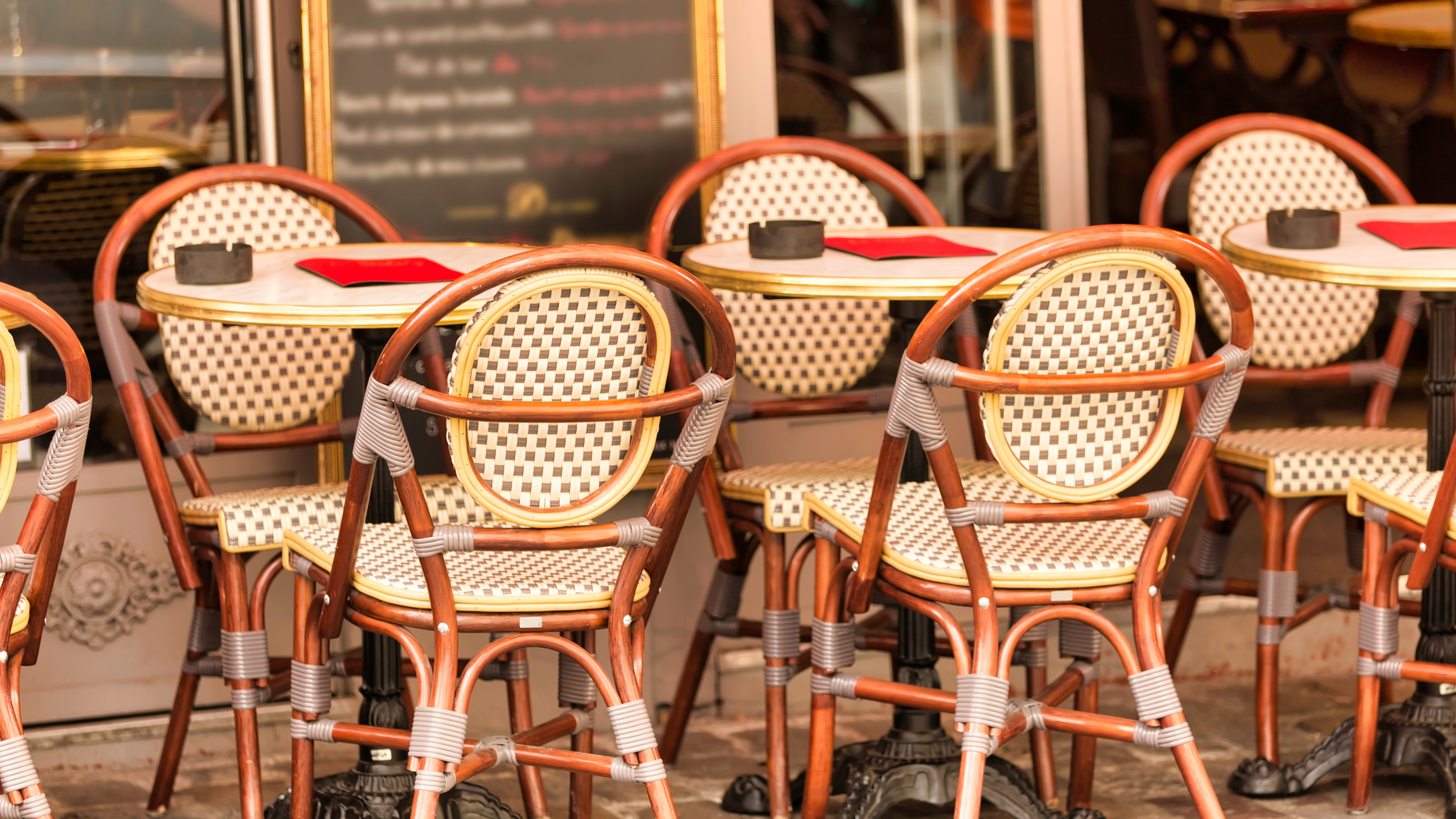 outdoor seating at a cafe with woven bistro chairs and round tables set
