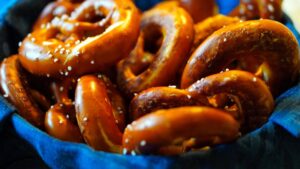 close up of soft pretzels with a golden brown crust sprinkled with coarse salt in a cloth lined basket
