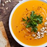 A bowl of pumpkin soup topped with pumpkin seeds.